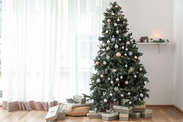 Decorated Christmas tree with pouf and presents near light curtain in living room