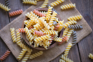 Pasta raw macaroni on wooden bowl background, close up raw macaroni spiral pasta uncooked delicious whole grain fusilli pasta for cooking food