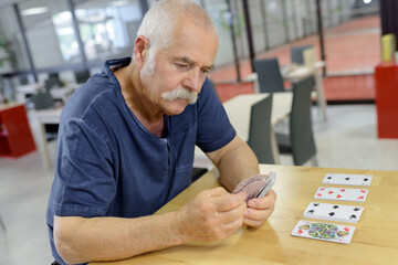 happy active retired man playing cards at home