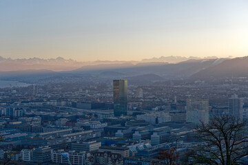 Aerial view over City of Zürich with skyscraper Prime Tower and Swiss Alps in the background on a sunny autumn evening. Photo taken December 6th, 2022, Zurich, Switzerland.