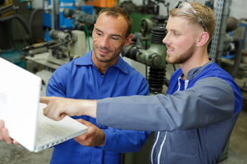 Obraz premium engineers in workshop looking at laptop