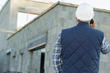 rear view of builder on telephone outside a new development