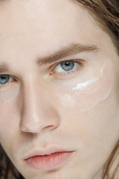 Close up beauty portrait shot of young male model with cream smear on his cheekbone