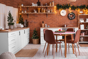 Interior of kitchen with Christmas trees, white counters and dining table