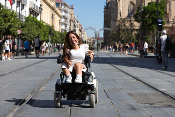 beautiful young disabled woman in wheelchair and reduced mobility enjoys her trip around the city where she is on vacation.
