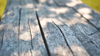 An old wooden table in a summer garden with rays of sunshine.