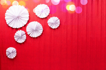 White paper rosettes on  red textured  paper background.  Handmade nordic decoration. Natural,...