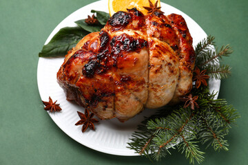 Plate with tasty ham, Christmas branches, spinach and anise on green background, closeup