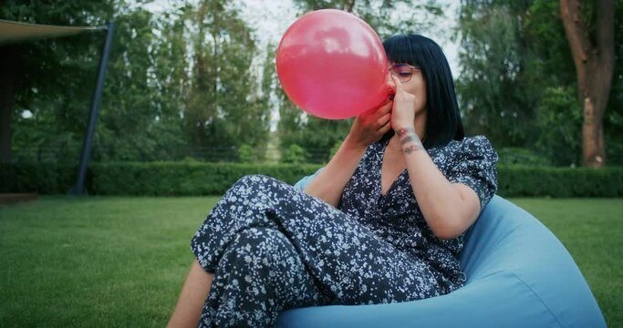 a joyful woman plays with balloons, imitating the reliability of condoms during sex, they will withstand any test and load.