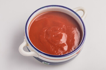 Tomato ketchup, ceramic cup on white background