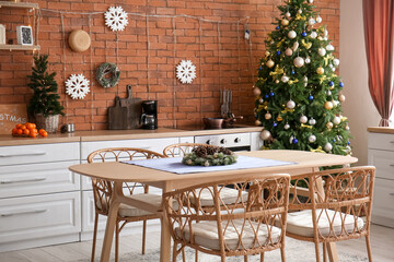 Dining table with Christmas branches and fir cones in kitchen