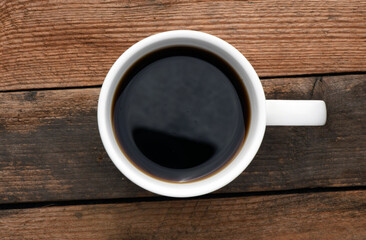 White cup with coffee on a wooden table.