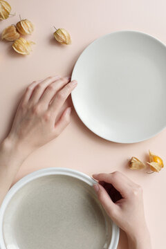From above shot of young woman&rsquo;s hands, plates and ground cherries on table