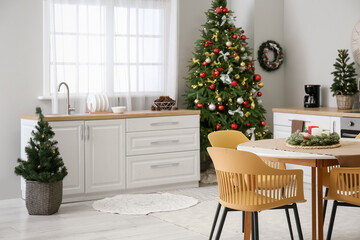 Interior of kitchen with Christmas trees, white counters and dining table