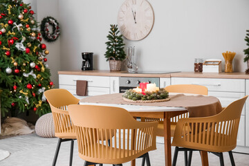 Dining table with Christmas branches and candles in interior of kitchen