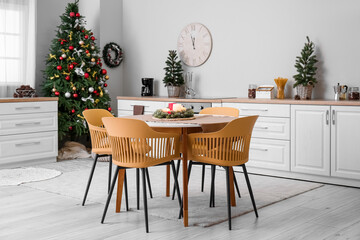 Interior of kitchen with Christmas trees, white counters and dining table