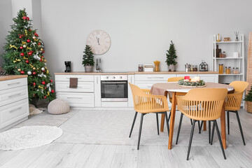 Interior of kitchen with Christmas trees, white counters and dining table