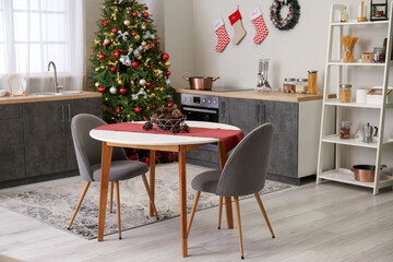 Fototapeta na wymiar Interior of kitchen with Christmas tree, counters and dining table