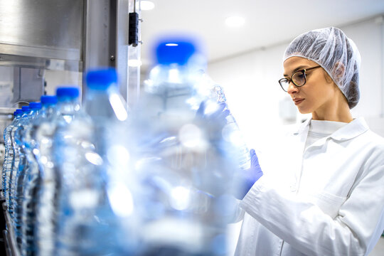 Experienced caucasian female employee working in bottling factory production line.