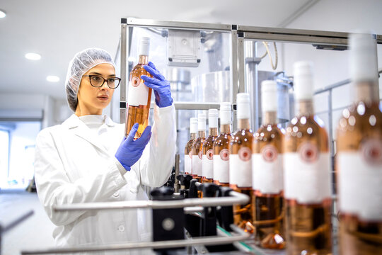 Female factory supervisor controlling wine production in alcohol beverage bottling plant.