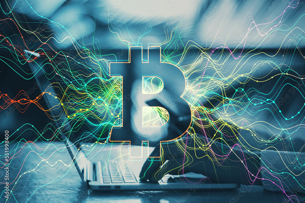 Poster close up of male hands using laptop on desktop with glowing bitcoin hologram on blurry outdoor backg