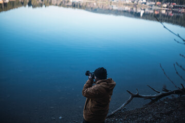 Man is taking pictures on a lake shore