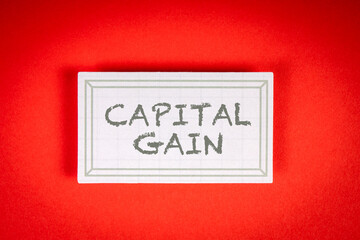 CAPITAL GAIN. Sticky note with text on a red background