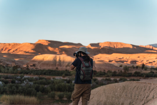young hipster taking pictures with his camera in the desert