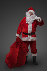 Photo of cheerful santa dressed in christmas red clothes against gray background.