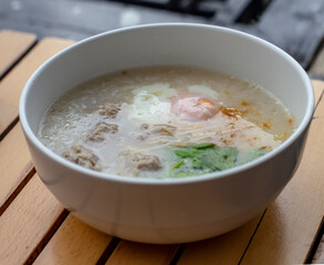 Pork boiled rice with egg in white bowl on wooden table