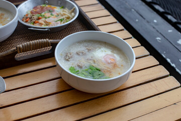 Pork boiled rice with egg in white bowl on wooden table