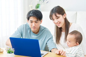 Obraz premium 家で赤ちゃんとパソコンを見る両親