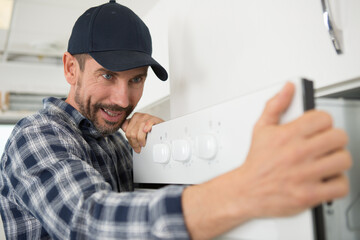 man fitting new cooker in kitchen