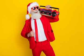 Fototapeta na wymiar Portrait of positive overjoyed aged person carry boombox enjoy newyear occasion isolated on yellow color background