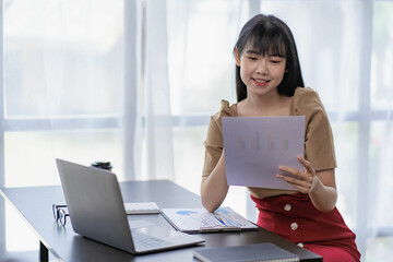 Asian businesswoman working with laptop computer Calculate, analyze, young woman, financial advisor, prepare statistical report, study documents, check financial charts in the office.