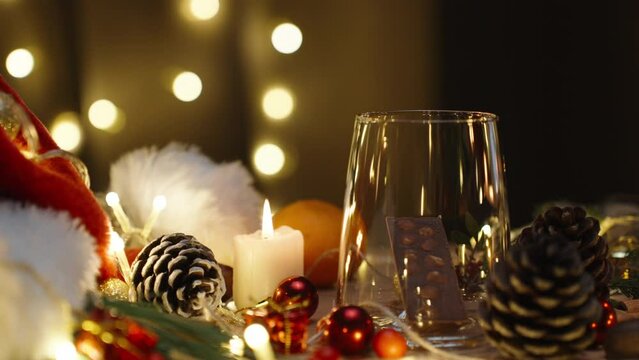 I make a drink from chocolate and cocoa. Christmas table with decorations and sweets. Candles and a garland are burning. Slow motion.
