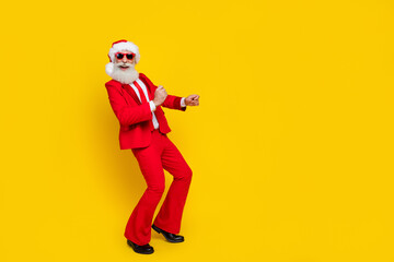 Fototapeta na wymiar Full length photo of handsome pretty man pensioner dressed red suit santa hat having fun empty space isolated yellow color background