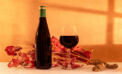 Verre de vin rouge avec une bouteille de vin sans étiquette avec en arrière plan des feuilles de...