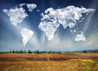 clouds in the form of a map of the world over the field. Travel and landscape concept. hilly field
