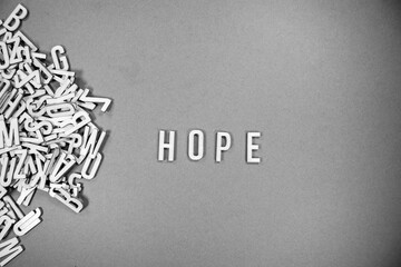 background with a pile of wooden capital letters spilling into words - HOPE - black and white