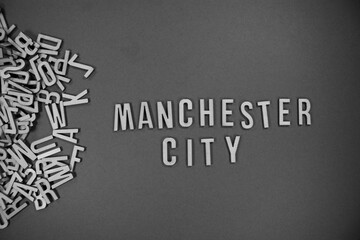 pile of wooden English language capital letters spilling into words - MANCHESTER CITY in black and white