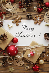 greeting card with Christmas tree branches, gingerbread cookies, gift boxes and ornaments on wooden background