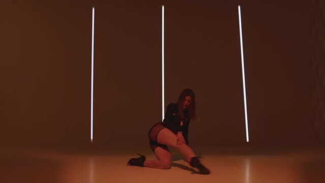 Music video shooting. Dancing girl cool sexy moving on studio floor. Female dancer wearing heels performs voguing dance
