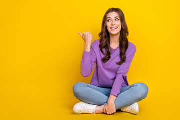 Full length portrait of cheerful nice person sit floor look direct finger empty space isolated on yellow color background - obrazy, fototapety, plakaty