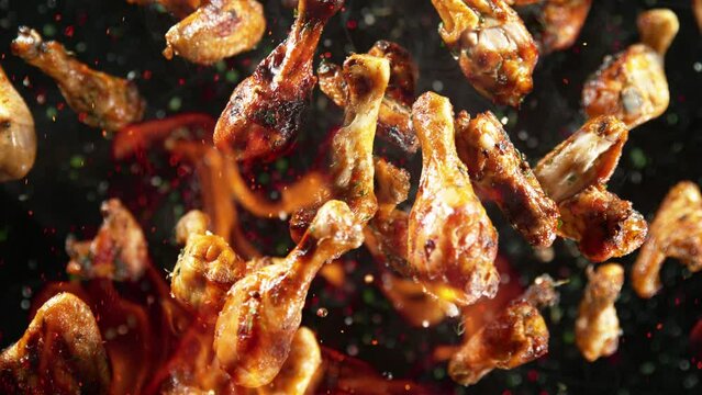 Super Slow Motion Shot of Grilled Spicy Chicken Wings and Drumsticks Flying Towards at 1000fps.