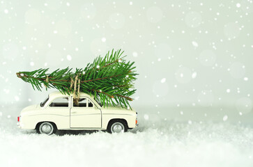 White car with christmas tree on snowy winter background. Merry Christmas and Happy New Year concept