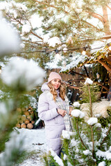 Winter portrait of a young pretty girl among pine branches outdoors