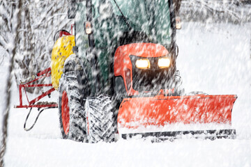 Tractor cleaning urban park paths on a cold snowy day.