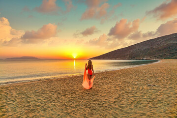 Young woman looking the sunrise from Agia Theodoti beach in Ios, Greece