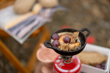Cheese melts in pan on a gas burner during a picnic in mountains